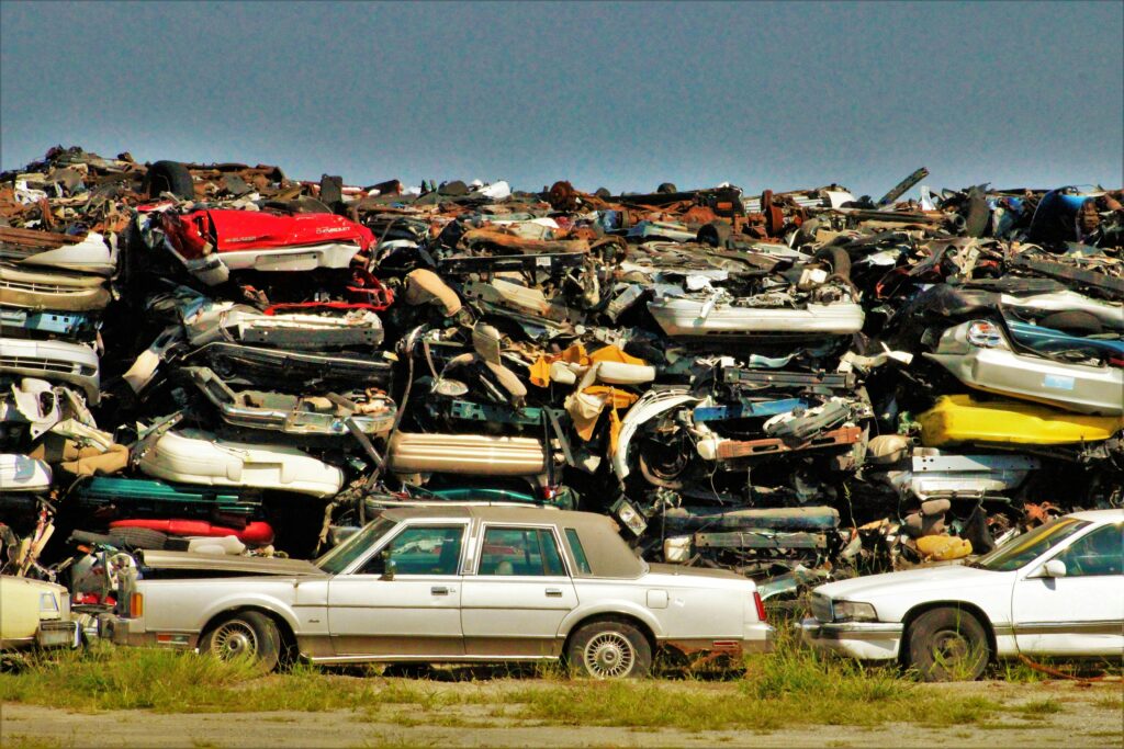 A large stack of disposed vehicles in an outdoor junkyard.